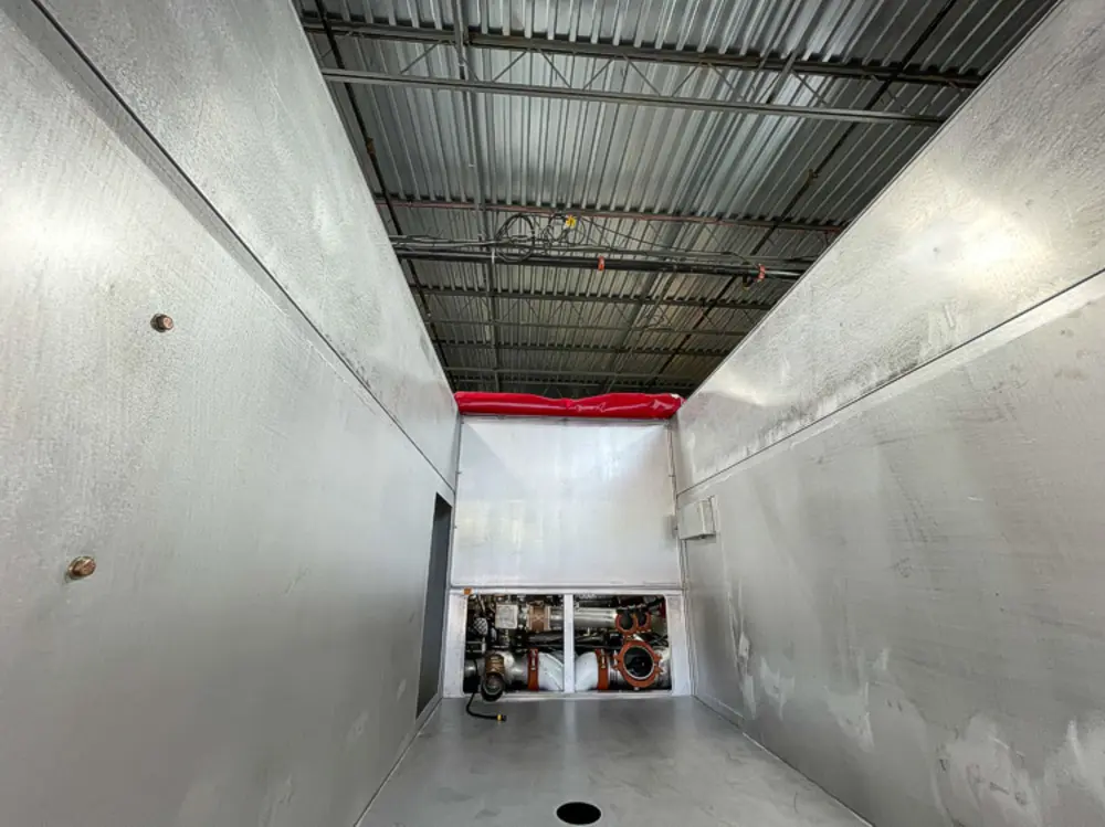 Exterior view of small fire truck showing cab, body compartments, and wheel/tire area.